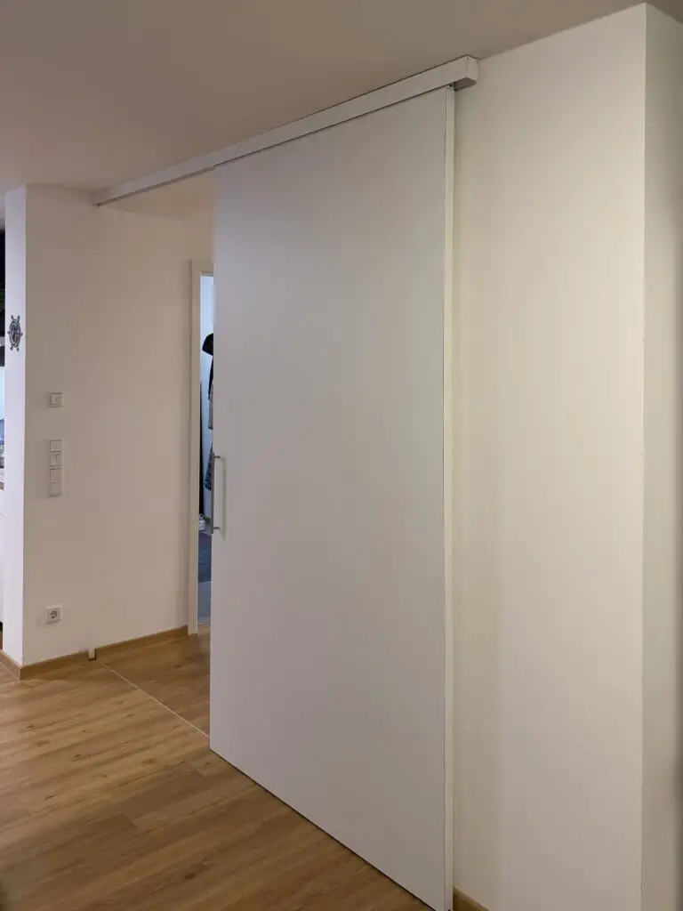 Raumhohe Schiebetür in Weiß mit Muschelgriff und Weißer Schiene